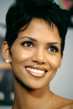 a close up of a person wearing a necklace and smiling at the camera with a smile on her face