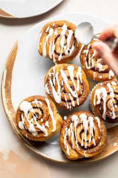 a plate filled with cinnamon buns covered in icing and drizzled