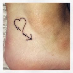 a small heart with an arrow tattoo on the side of her foot is shown in black ink