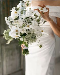 a bride holding a bouquet of white flowers