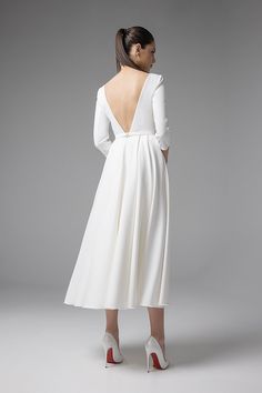 the back of a woman's white dress with long sleeves and open - back