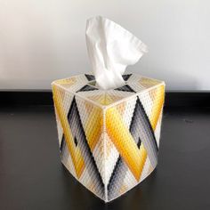 a tissue paper dispenser sitting on top of a black table next to a white wall