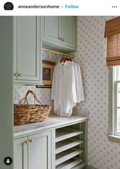 a laundry room with green cabinets and wallpaper