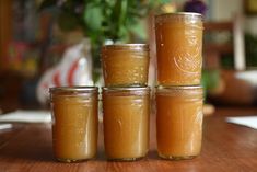 four jars filled with liquid sitting on top of a wooden table