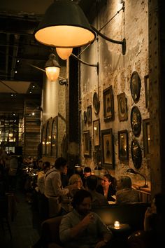 people sitting at tables in a dimly lit restaurant with pictures on the wall behind them