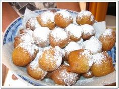 a blue and white plate filled with powdered sugar covered donuts on top of a table