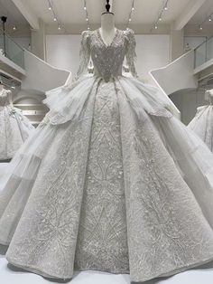 a white wedding dress on display in a room with other gowns and dresses behind it