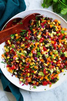 a white bowl filled with chopped vegetables on top of a marble counter next to a wooden spoon