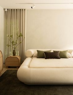 a large white bed sitting in a bedroom next to a window