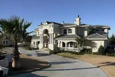 a large white house with palm trees in the front yard