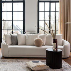 a white couch sitting in front of two large windows