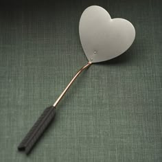 a white heart shaped object with an arrow sticking out of it's side on a green surface