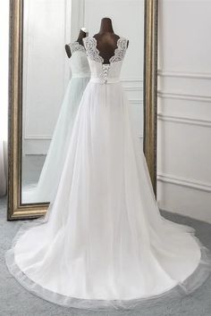 a white wedding dress is on display in front of a mirror with a long train