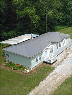 an aerial view of a house in the middle of a field with trees behind it