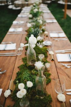 the long table is covered with moss and white flowers