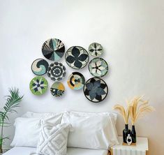 a white bed topped with lots of pillows next to a wall mounted clock on the wall