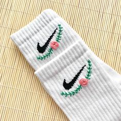 two pairs of white socks with pink roses on the bottom and black nike logo on the side