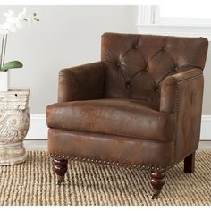 a brown leather chair sitting on top of a rug next to a vase with flowers