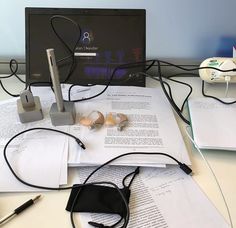 a computer monitor sitting on top of a desk next to papers and other electronic equipment