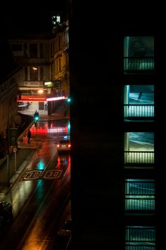 the city street is lit up at night with cars driving down it's road