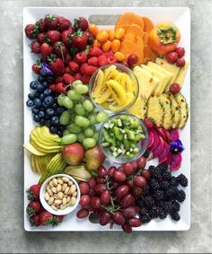 a platter filled with fruits and vegetables on top of a white plate next to nuts