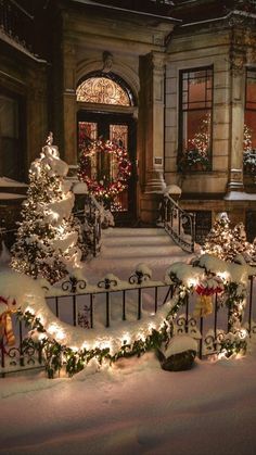 christmas lights are on the fence in front of a building with a gate and trees