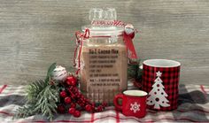 a glass jar sitting on top of a table next to two mugs and christmas decorations