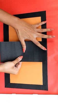 two hands on top of an orange and black piece of paper