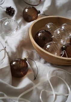 some glass balls in a wooden bowl on a white table cloth with twine cord