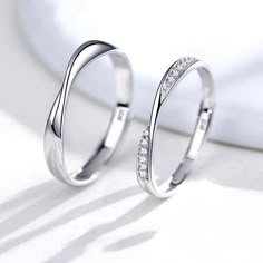 two white gold wedding rings with diamonds on top of each other in front of a white background