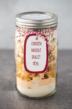 a glass jar filled with food sitting on top of a wooden table next to a red and white tag