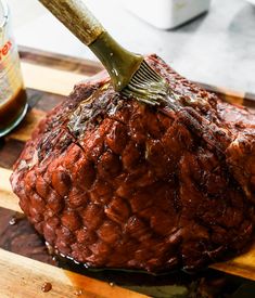 a large piece of meat on a cutting board with a brush sticking out of it