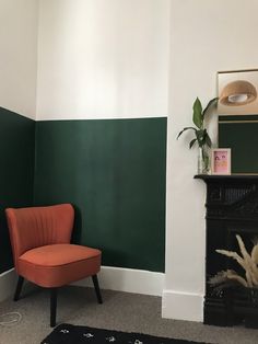 an orange chair sitting next to a fireplace in a room with green and white walls