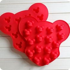 two mickey mouse heart shaped cake pans on a white table with wood planks