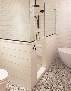 a white bathroom with black and white floor tiles on the shower wall, toilet and bathtub