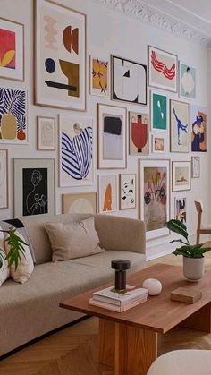 a living room filled with furniture and lots of pictures on the wall next to a coffee table