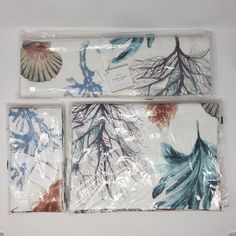 three placemats with blue and red leaves on them in clear plastic wrappers