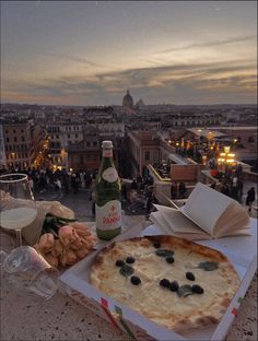 a pizza sitting on top of a table next to a bottle of wine and other food