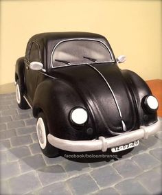 a cake in the shape of a black car on a table with a brick floor