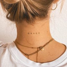 a woman with a tattoo on her neck that reads grace and is wearing a gold chain