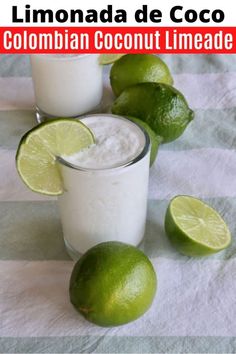 two glasses filled with ice and limes next to each other on a striped cloth