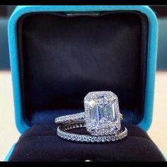 an emerald cut diamond ring in a blue velvet box with its reflection on the surface