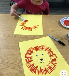 a little boy sitting at a table with paper cut out to look like a lion