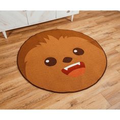 a brown rug with a face on it in the middle of a wooden floor next to a white cabinet