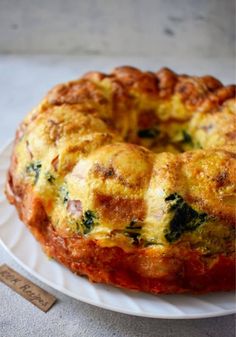 a bundt cake sitting on top of a white plate covered in cheese and spinach