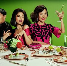 three people sitting at a table with food and drinks in front of them, posing for the camera