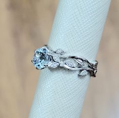 a white gold ring with an aqua blue topazte and diamond accents on it