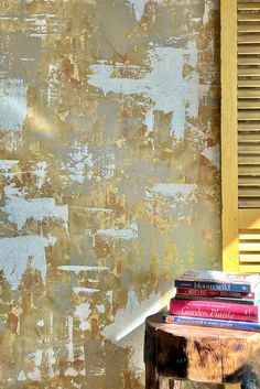 a stack of books sitting on top of a wooden table next to a yellow wall