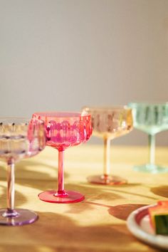 several wine glasses sitting on top of a wooden table next to plates and utensils