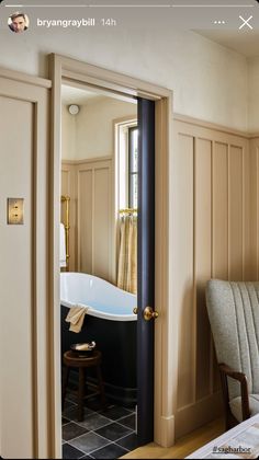 an open door leading to a bathroom with a bathtub in the corner and a chair next to it